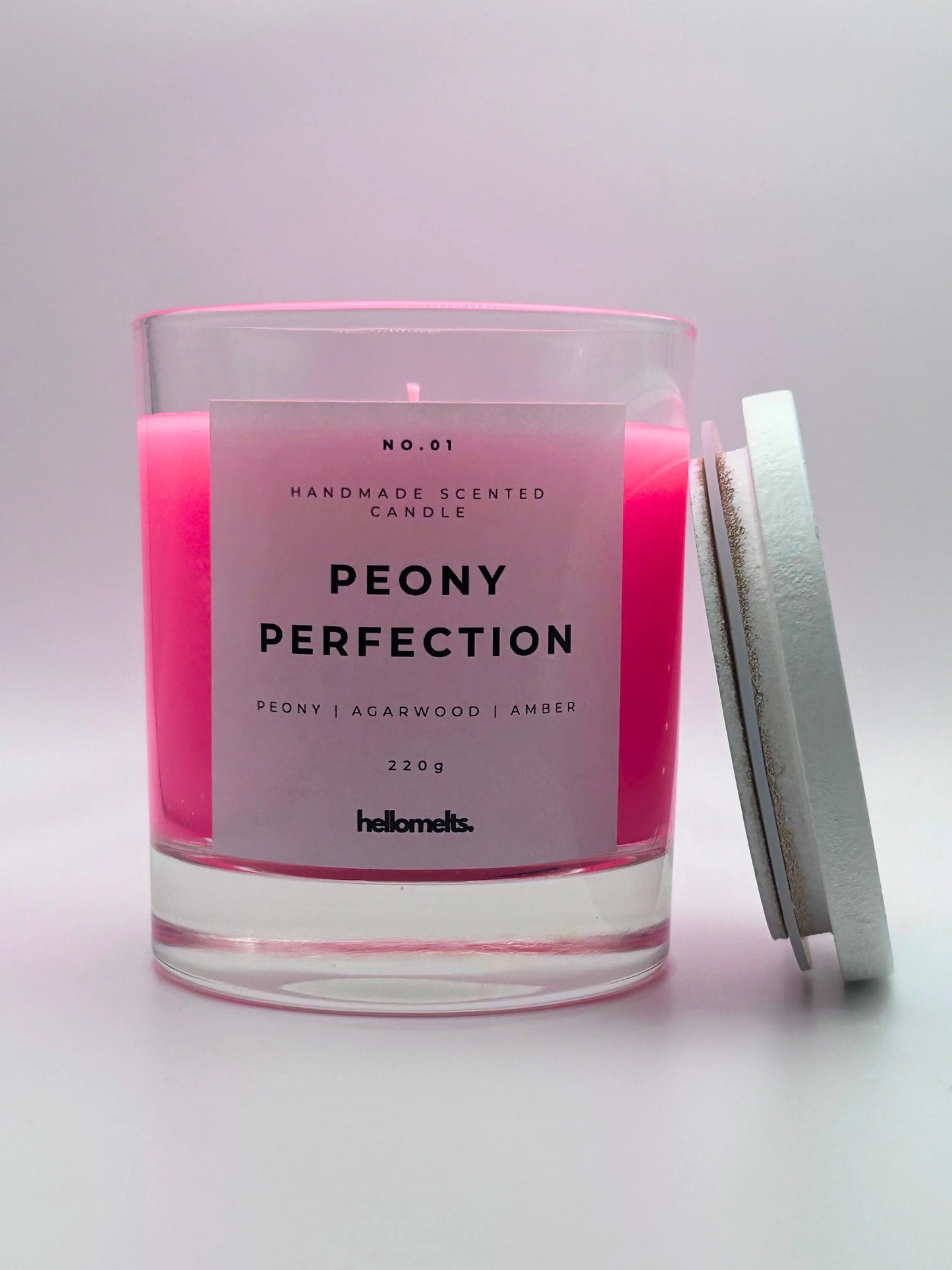 Peony Perfection 220g candle, with lid beside jar, by Hellomelts, exuding delicate peony, luxurious agarwood, and warm amber aromas, in a beautiful bright pink wax.