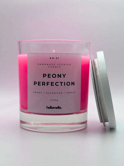 Peony Perfection 220g candle, with lid beside jar, by Hellomelts, exuding delicate peony, luxurious agarwood, and warm amber aromas, in a beautiful bright pink wax.