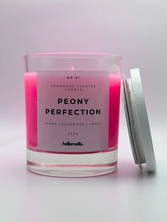 Peony Perfection 220g candle, with lid beside jar, by Hellomelts, exuding delicate peony, luxurious agarwood, and warm amber aromas, in a beautiful bright pink wax.