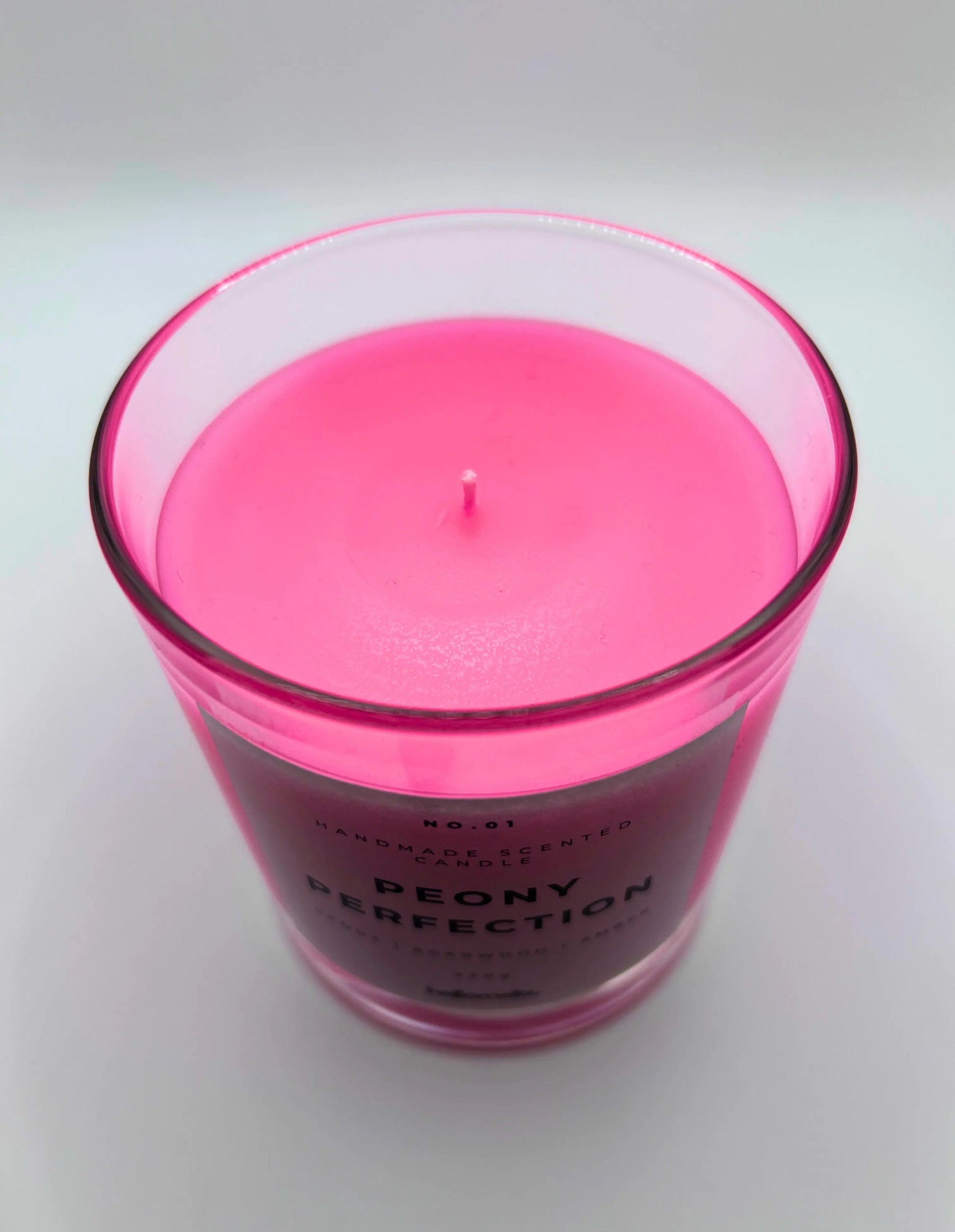 Peony Perfection 220g candle, showing top of jar with lid off, by Hellomelts, exuding delicate peony, luxurious agarwood, and warm amber aromas, in a beautiful bright pink wax.