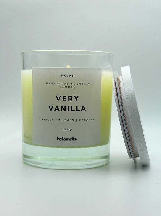 Very Vanilla 220g candle by Hellomelts, with lid beside jar, infused with the warm scents of vanilla, nutmeg, and caramel, showcased in a simple white wax.