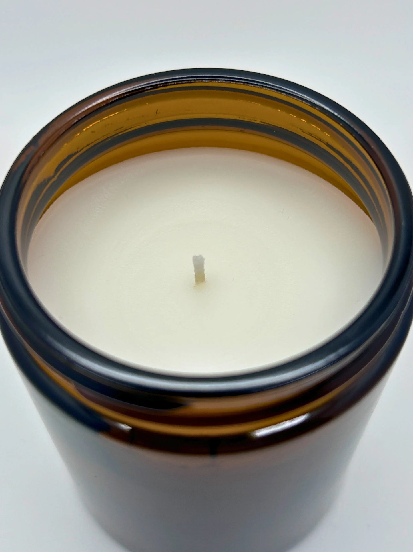 Close-up angled top view of Cedarwood & Amber candle by Hellomelts, showcasing the smooth wax in an amber jar from the autumn collection.